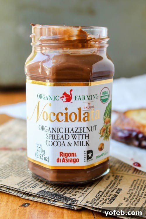 A jar of Nocciolata hazelnut spread next to fresh raspberries