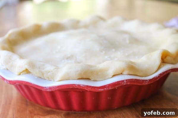 Adding Top Pie Crust Placing the top pie crust over the filled Rhubarb Custard Pie using parchment paper.