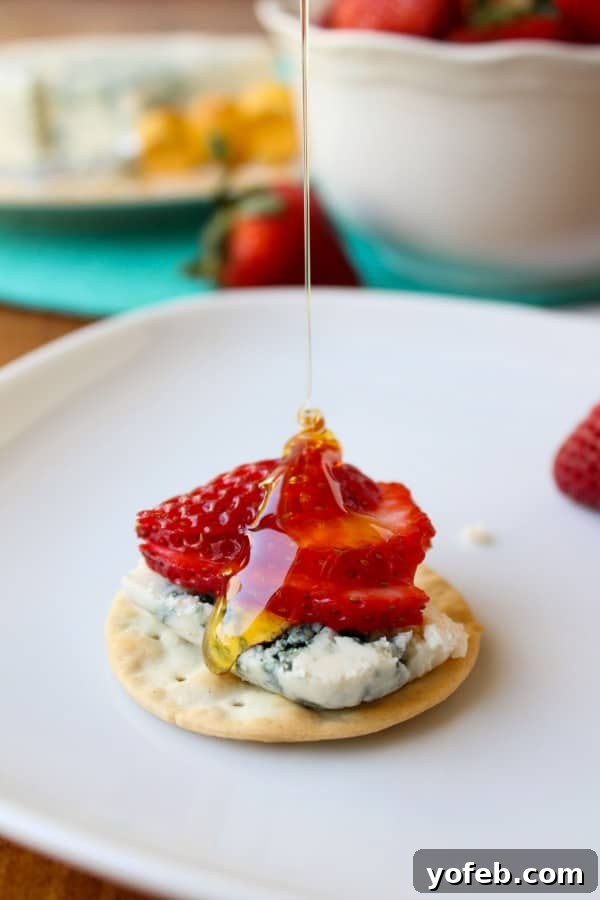 Honey-Drizzled Bleu Cheese Strawberry Jewels 3 Ingredients for Honey-Drizzled Bleu Cheese Strawberry Bites arranged on a wooden board.