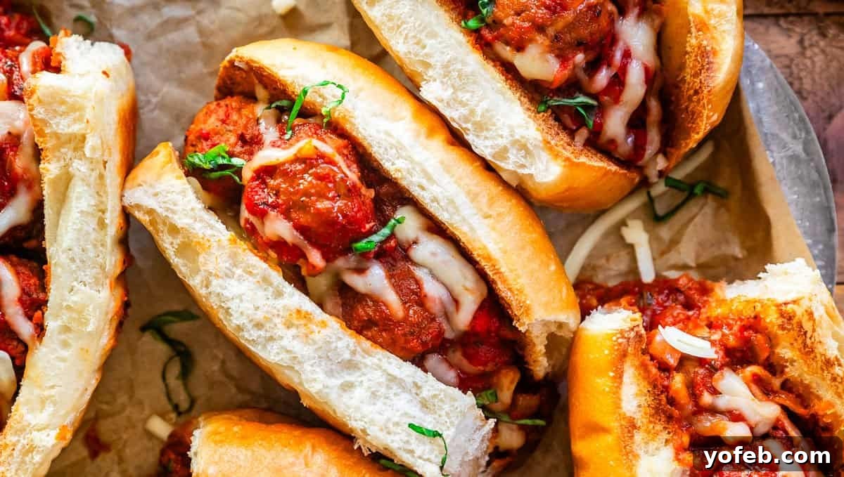 Meatball sub on parchment paper with meatballs, marinara, and garnishes of melted mozzarella and parsley, ready for a game day feast.