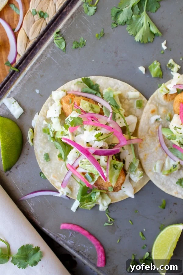 Homemade Beer Battered Fish Tacos with Cabbage Slaw Arrangement of beer-battered fish, shredded cabbage slaw, and vibrant pickled onions on corn tortillas, ready for assembly.