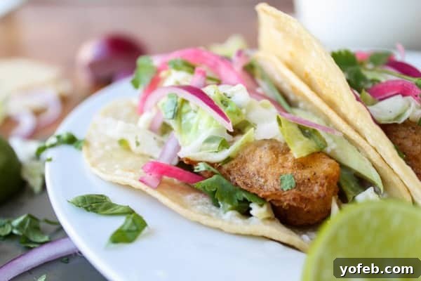 Perfectly Crispy Beer Battered Fish Taco Close-up of a single beer-battered fish taco, showcasing the crispy fish, fresh slaw, and vibrant pickled red onion on a corn tortilla.