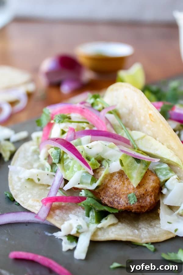 Close Up of a Delicious Baja Fish Taco Detailed close-up of a beer-battered fish taco, featuring crispy fish, vibrant red onion, and fresh slaw on a corn tortilla.