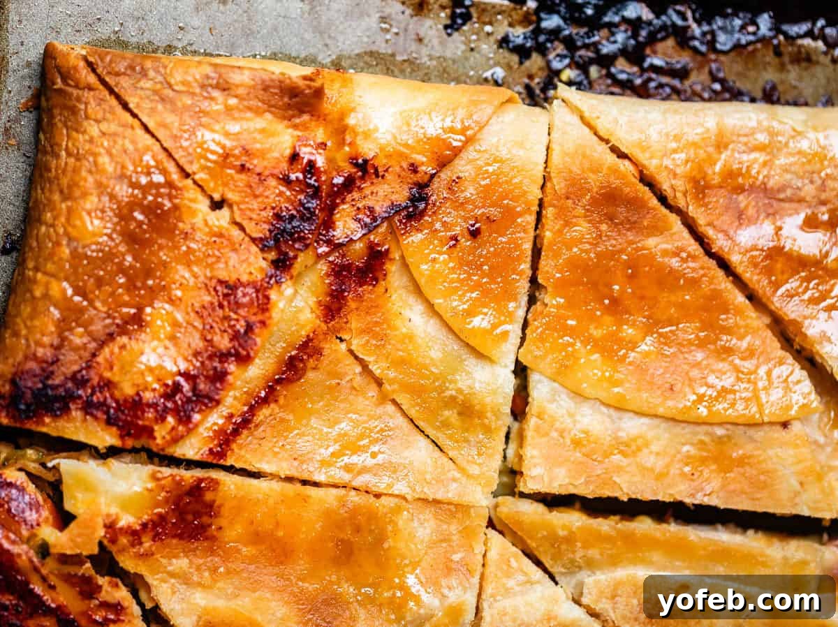 Crispy Sheet Pan Chicken Quesadillas 15 Close-up of golden, flaky baked quesadillas cut into triangular pieces on a baking sheet.