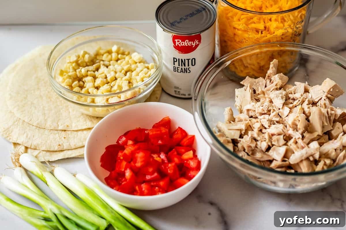 Crispy Sheet Pan Chicken Quesadillas 7 A marble countertop with tortillas, chopped green onions, diced tomatoes, cooked corn, shredded cheddar cheese, a can of pinto beans, and a bowl of chopped cooked chicken.