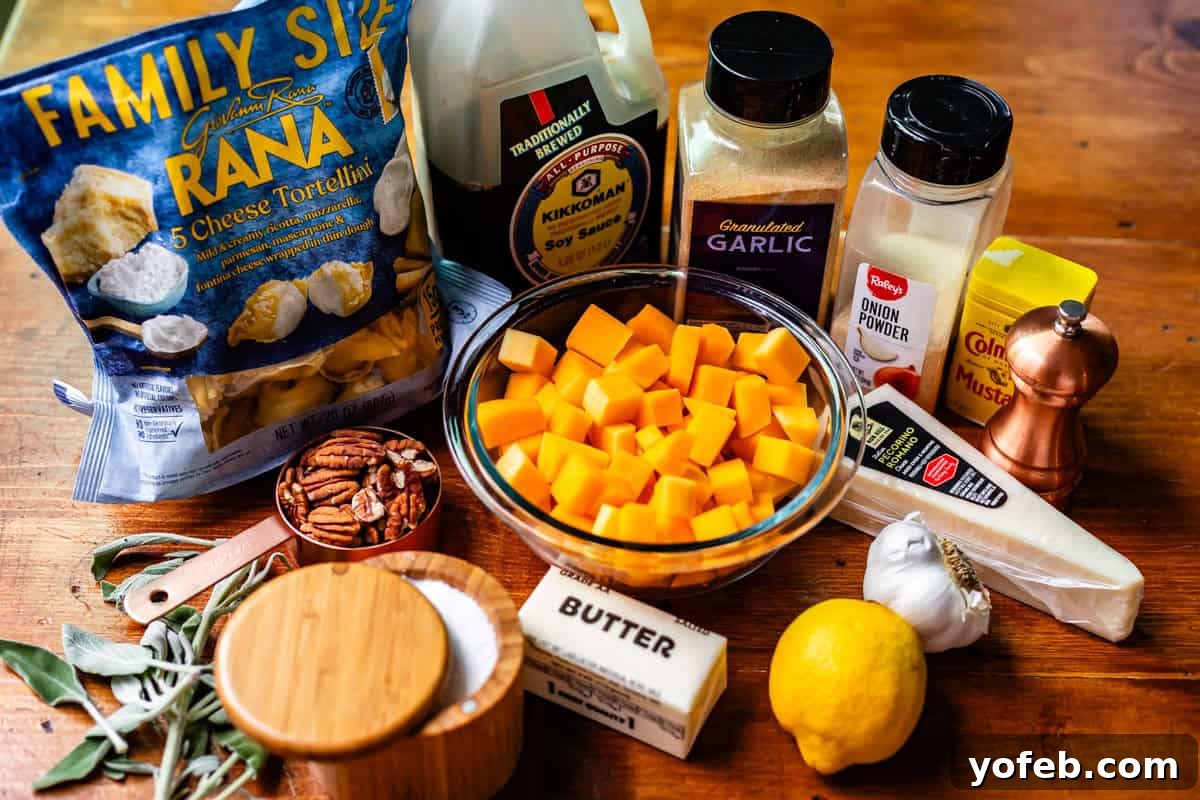 Butternut Bliss Tortellini 6 A variety of cooking ingredients on a wooden surface, including a bag of cheese tortellini, cubed butternut squash, butter, parmesan cheese, seasonings, soy sauce, lemon, pecans, and fresh sage leaves.