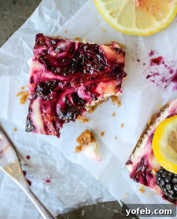 Zesty Lemon Blackberry Squares 5 A single blackberry lemon cheesecake bar with a bite taken out, highlighting the rich, creamy texture and fruit swirl.