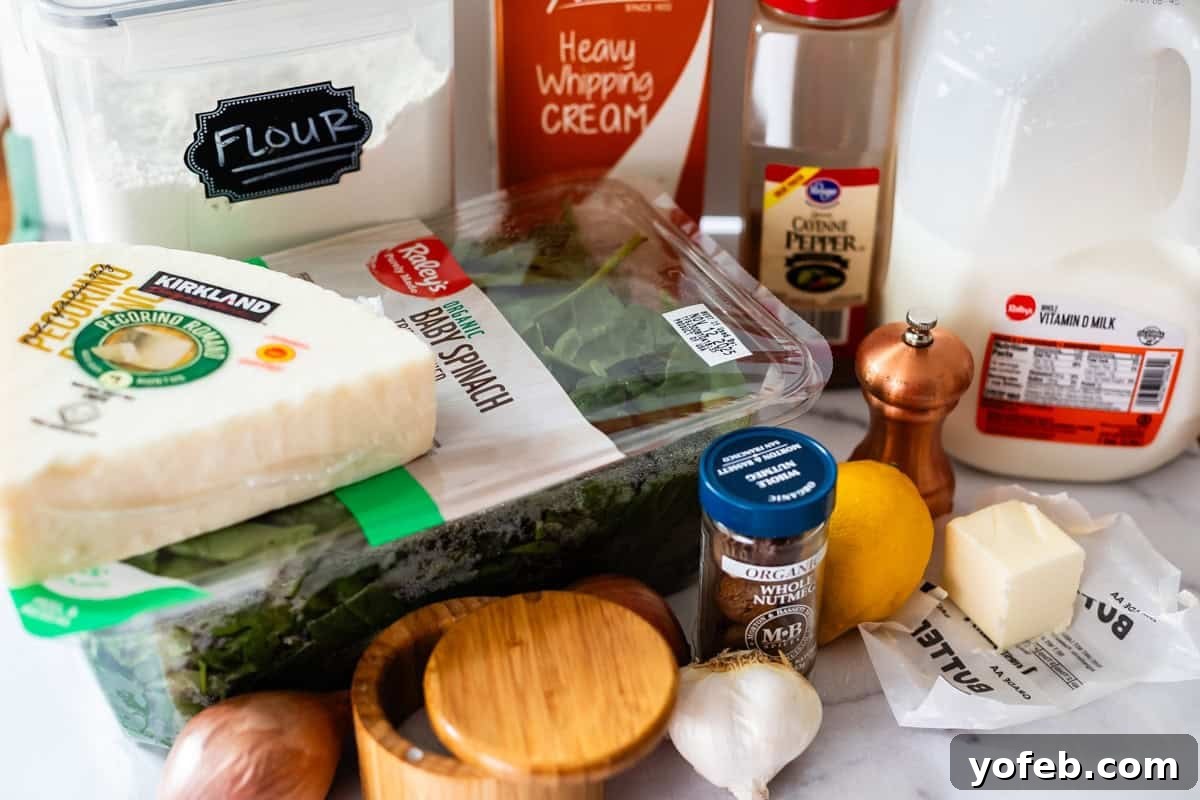 A collection of cooking ingredients on a countertop, including flour, heavy whipping cream, milk, pecorino cheese, baby spinach, black pepper, a lemon, garlic, nutmeg, butter, and a wooden salt container.