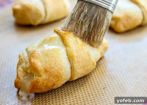 Brushing Reuben crescent rolls with melted butter after baking
