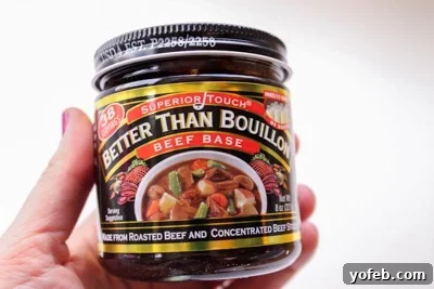 Hearty Slow-Simmered Beef Barley Soup 4 A hand holding a jar of Better Than Bouillon Beef Base, a key ingredient for rich soup flavor.
