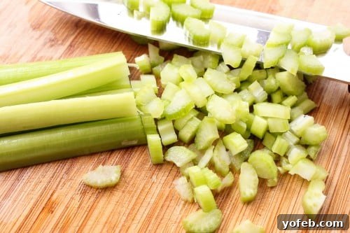 Hearty Slow-Simmered Beef Barley Soup 6 Celery stalks being chopped on a wooden cutting board, a fresh aromatic for the soup.