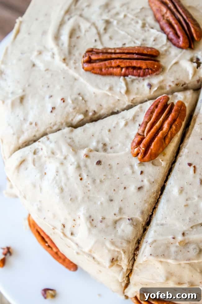 A slice of carrot cake topped generously with maple pecan frosting, showing its creamy texture.