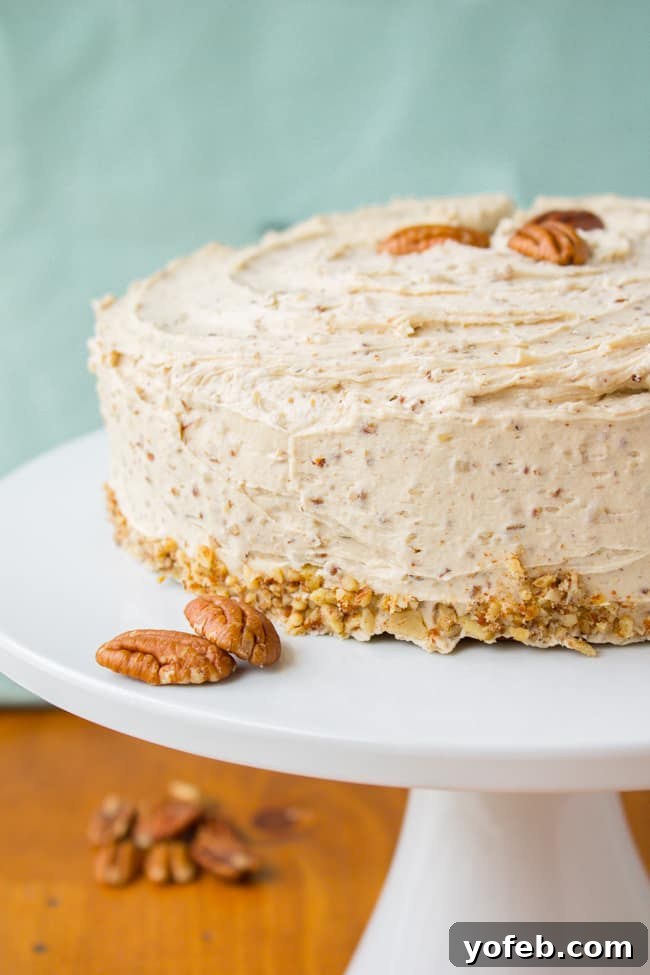 A beautiful Cinnamon Cardamom Cake adorned with Maple Pecan Frosting, displayed on a cake stand.