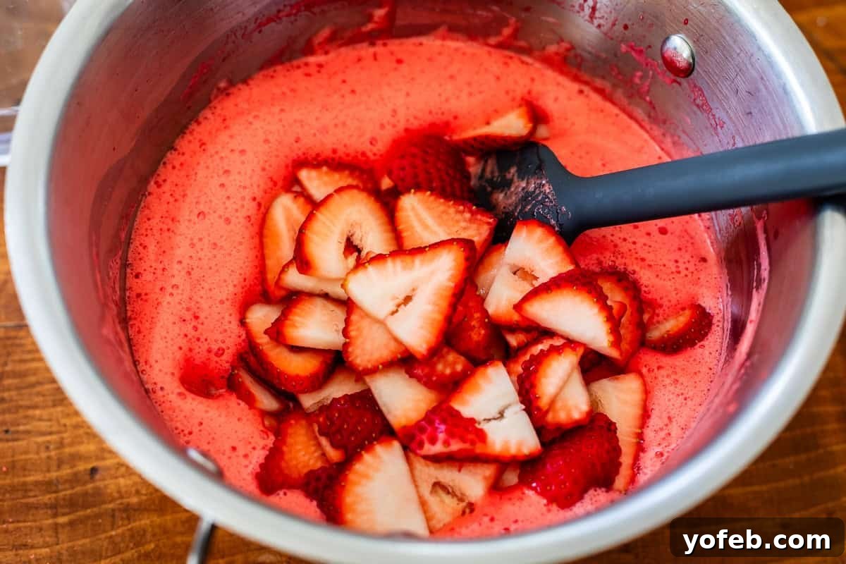 Sweet & Salty Pretzel Delight 16 mixing strawberries into liquid jello with a spatula.