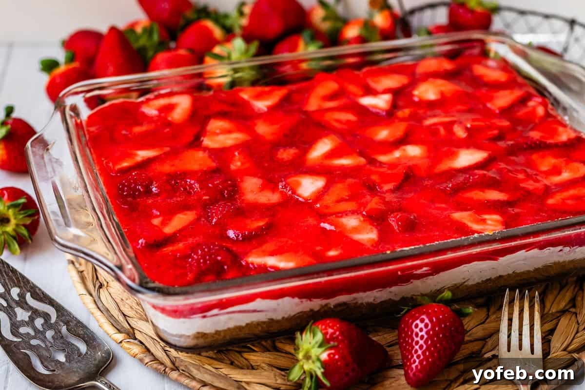 Sweet & Salty Pretzel Delight 18 completed strawberry jello pretzel salad with strawberries around it.