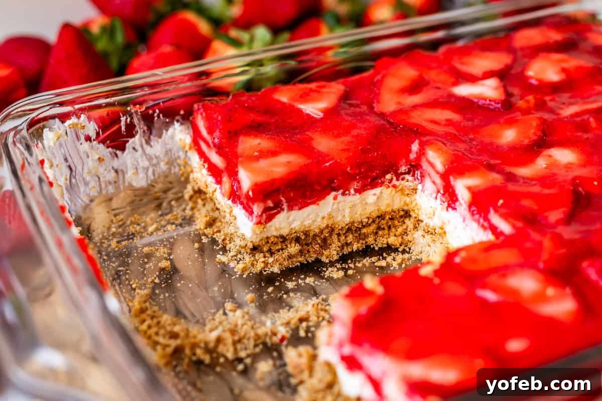 Sweet & Salty Pretzel Delight 20 strawberry jello pretzel salad in a pan with slices cut out of it.