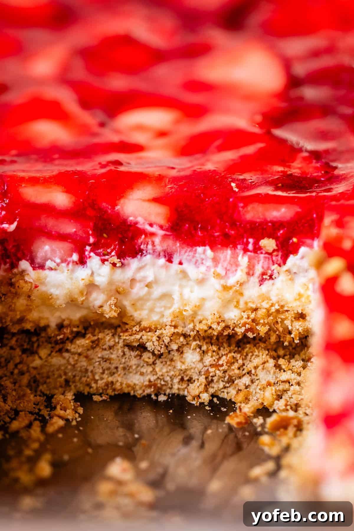 Sweet & Salty Pretzel Delight 21 close up shot of strawberry jello pretzel salad with a slice cut out of it.