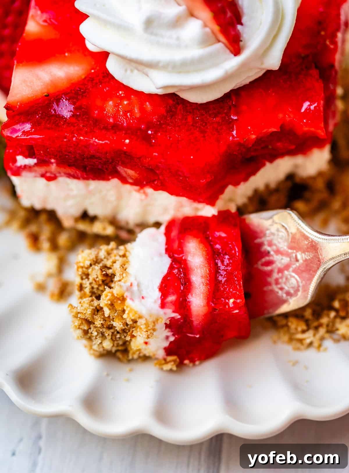 Sweet & Salty Pretzel Delight 4 a forkful of strawberry jello pretzel salad with topping and strawberries.