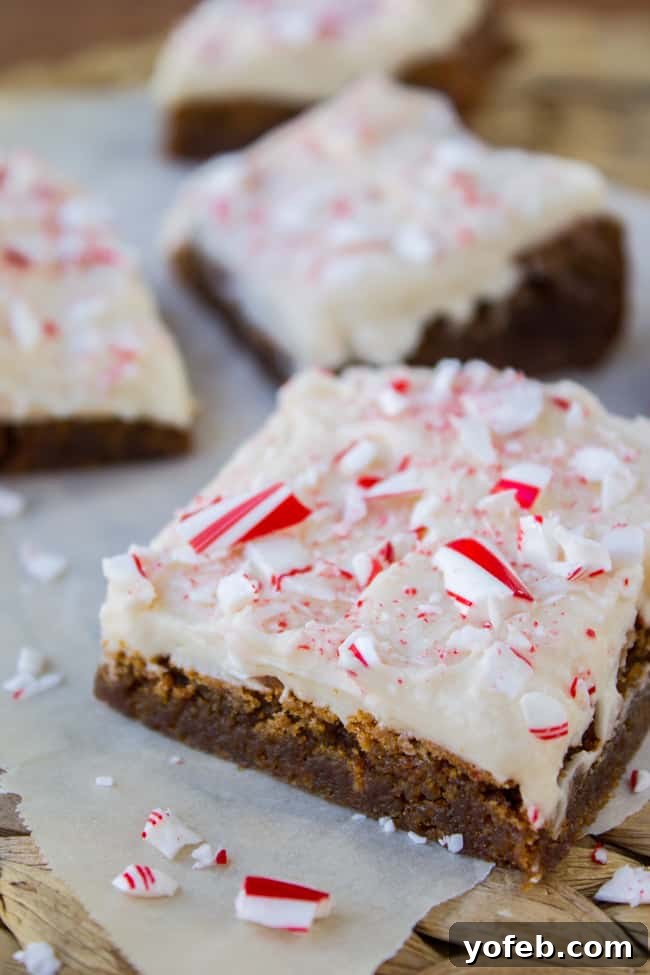 A freshly baked batch of Frosted Peppermint Gingerbread Bars, elegantly sliced and arranged for serving, adorned with a final sprinkle of crushed candy canes.