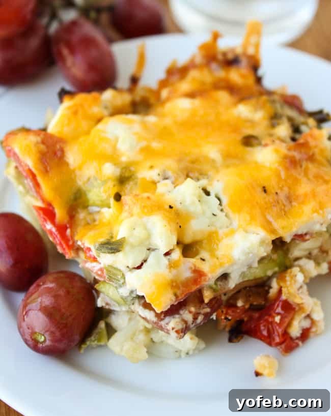 Spring Asparagus Egg Stratta 2 egg, bacon, and asparagus casserole on a plate with grapes.