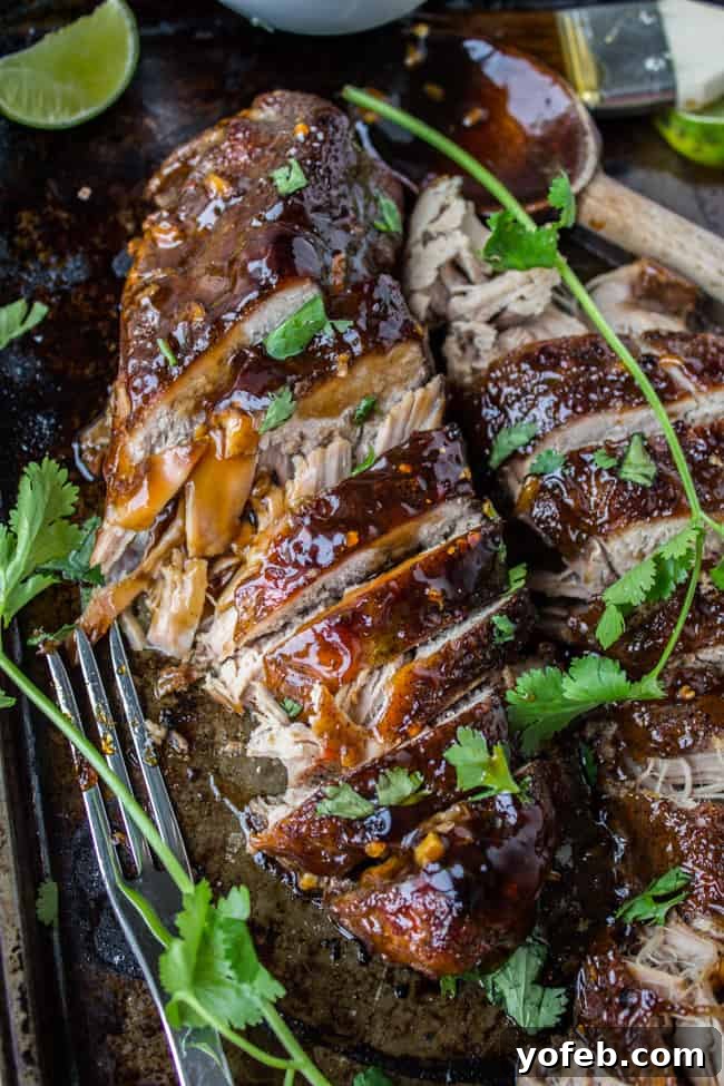 Savory Slow Cooker Asian Pork Tenderloin 4 sliced pork tenderloin with sticky sweet glaze, fresh cilantro, and lime wedges.