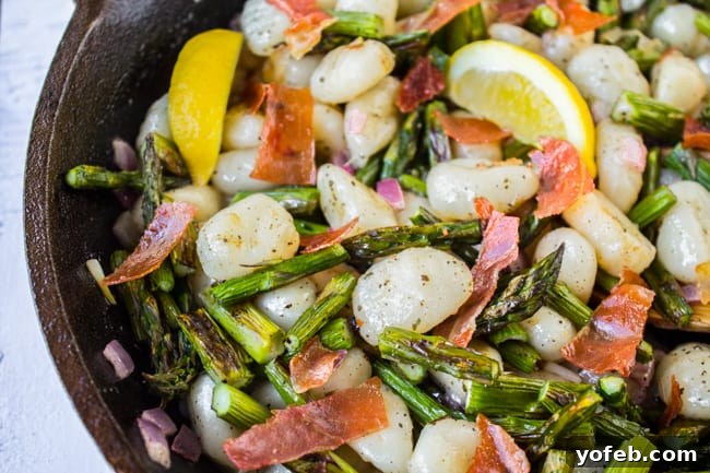 Nutty Brown Butter Gnocchi with Crisp Asparagus 4 A close-up of a cast iron pan showcasing tender gnocchi, bright green asparagus, and crispy prosciutto bathed in brown butter lemon sauce.
