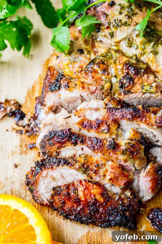 Zesty Cuban Mojo Pork Roast 3 Beautifully sliced Lechon Asado adorned with fresh cilantro and a bright orange slice.