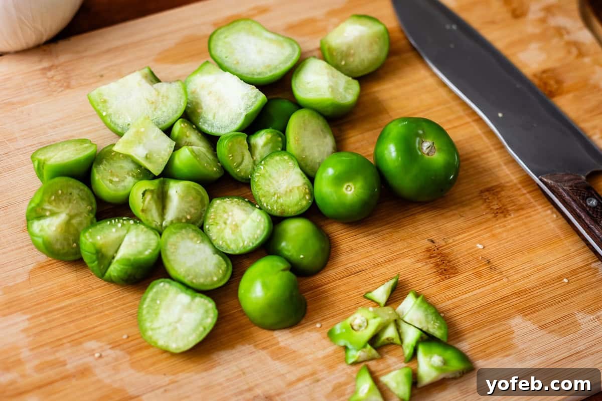 Vibrant Green Chicken Pozole in Minutes 11 Chopped and whole green tomatillos on a wooden cutting board next to a kitchen knife.
