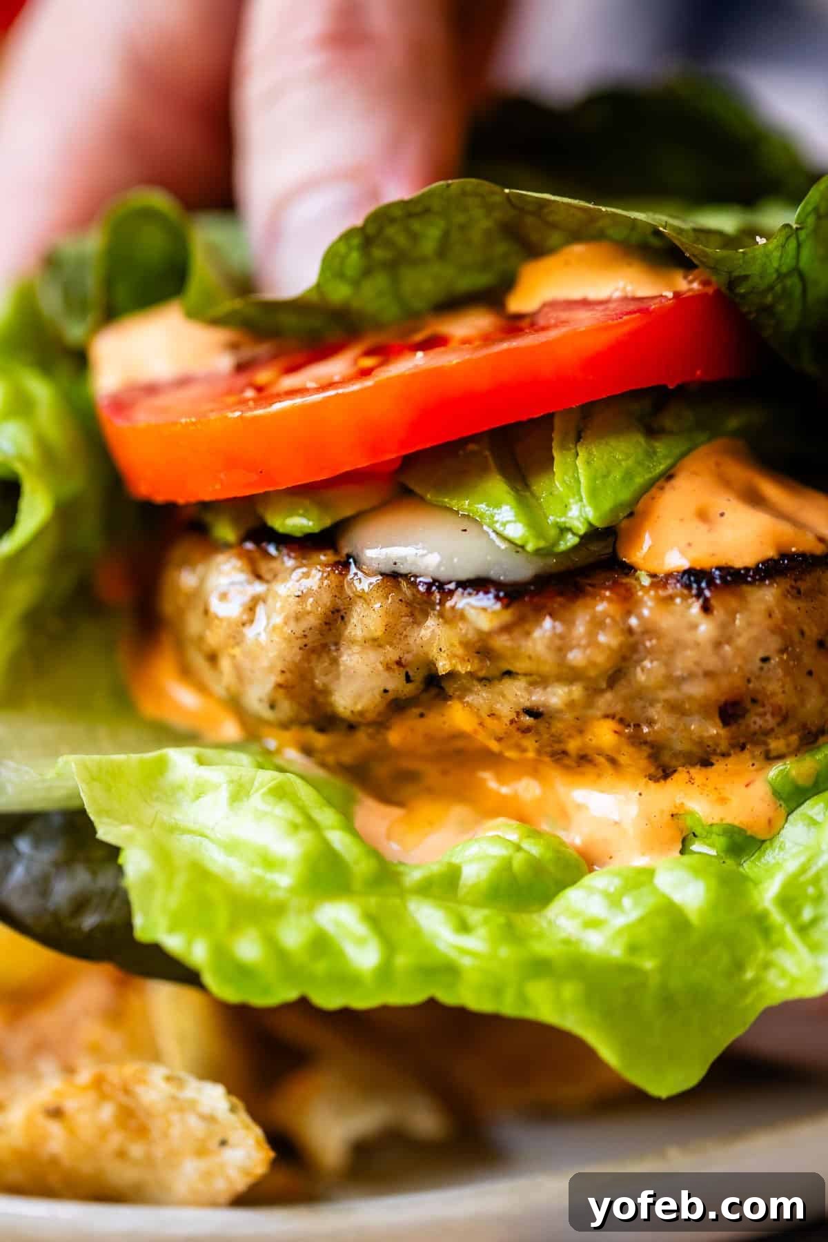 Game-Changing Turkey Burgers 14 An enticing close-up of a perfectly constructed burger, focusing on its generous, vibrant toppings and the appealing, juicy texture of the patty. Every detail is highlighted, inviting a delicious bite.