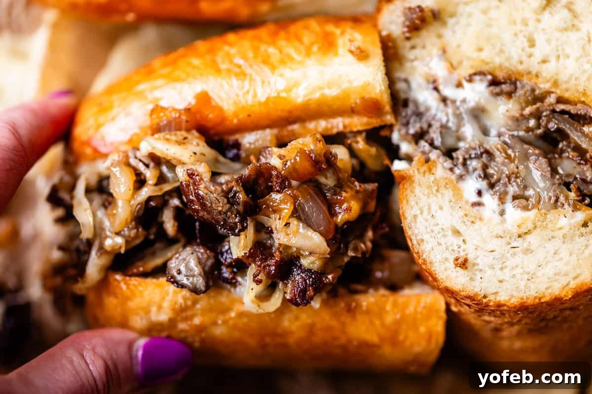 Authentic Philly Cheesesteak Recipe: How to Make It at Home 17 A close-up of a hand holding a cheesesteak sandwich filled with grilled steak, caramelized onions, and melted cheese, served in a toasted hoagie roll.