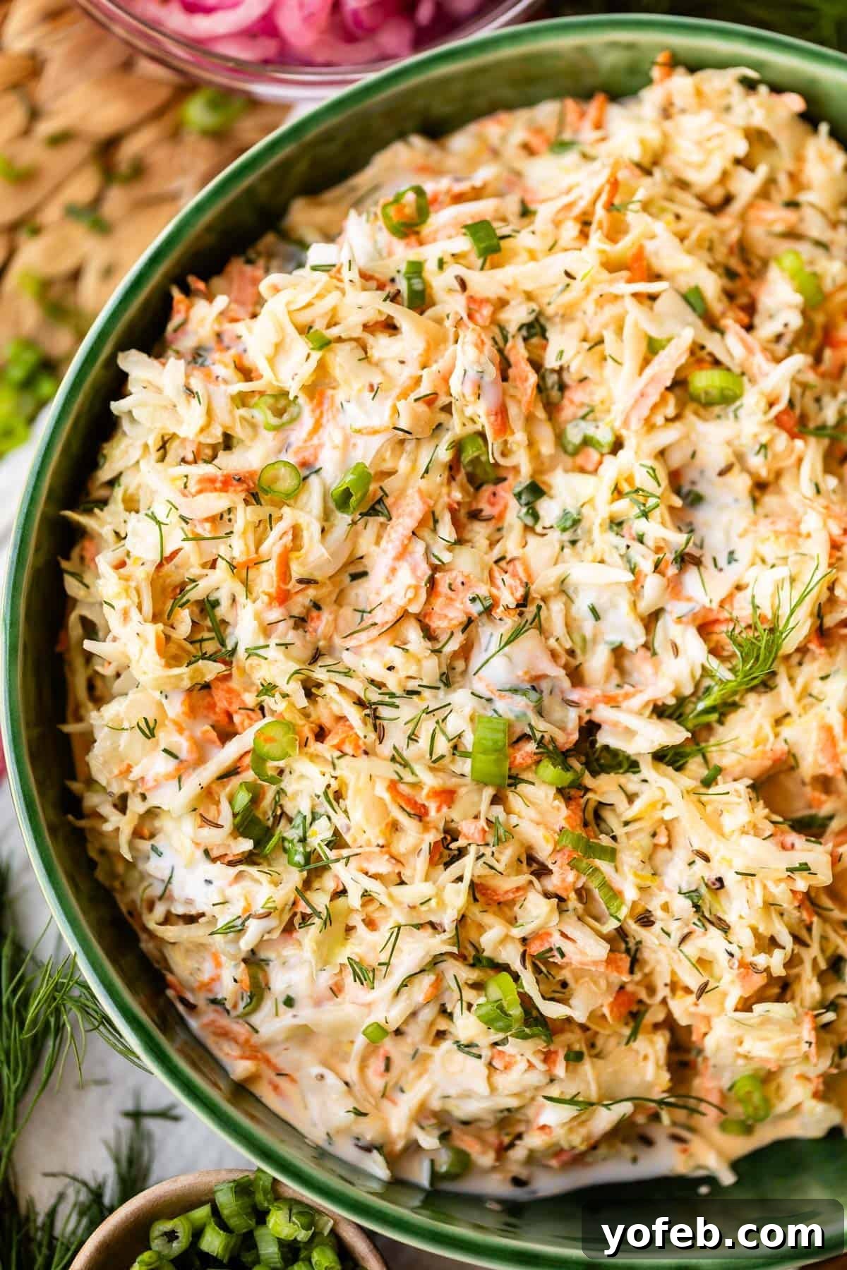 Classic Creamy Coleslaw Recipe with Tangy Dressing 3 A close-up of a bowl filled with creamy coleslaw, featuring shredded cabbage, carrots, and green onions, garnished with fresh dill.