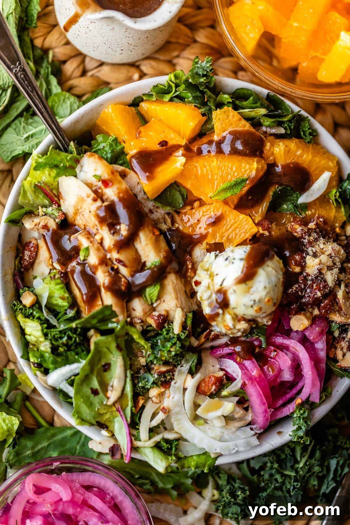 Mendocino Copycat Citrus and Goat Cheese Salad 17 A vibrant salad bowl with orange slices, grilled chicken, pickled onions, nuts, greens, goat cheese, and dark dressing, surrounded by extra pickled onions and citrus in small bowls.
