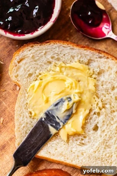 Soft Honey Whole Wheat Bread Recipe 16 a butter knife spreading softened butter on a single piece of homemade white bread .